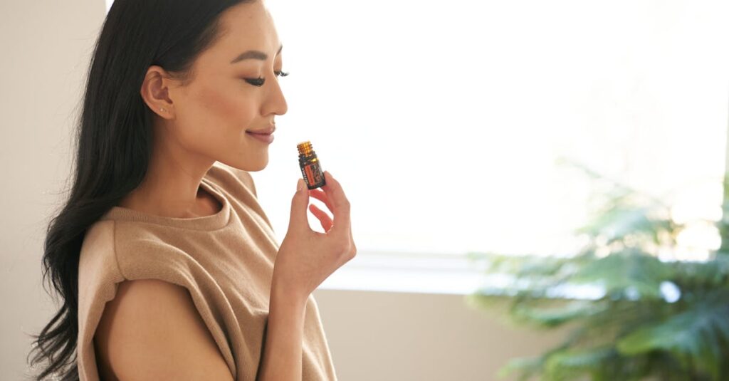Asian woman with closed eyes enjoying the aroma of essential oil in a calm indoor setting.
