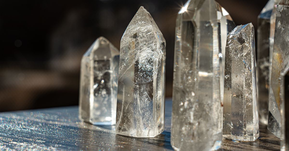 A detailed close-up of clear quartz crystals reflecting light with a blurred background.